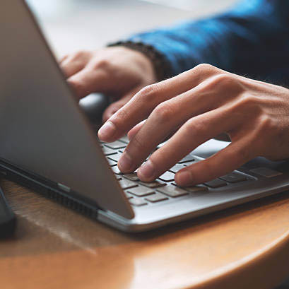 Close up of hands typing on laptop in coffee shop